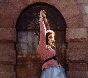 Woman in traditional clothing standing against brick wall