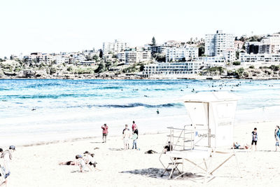 People at beach against sky in city