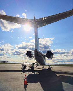 Engineers by airplane on airport runway against sky