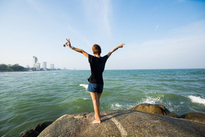 Rear view of woman on rock by sea