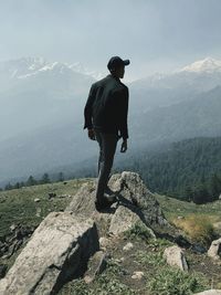 Rear view of teenage boy standing on rock