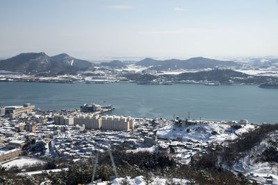 High angle view of city by sea against sky