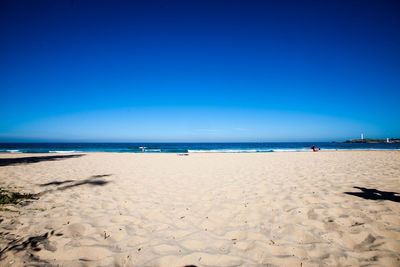 Scenic view of beach against clear blue sky