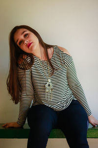 Portrait of woman sitting against wall at home