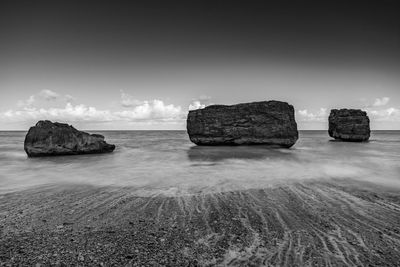 Rocks on sea shore against sky