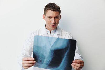 Portrait of doctor standing against white background