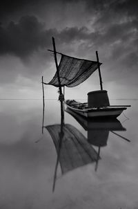 Fishing boat moored on lake against sky