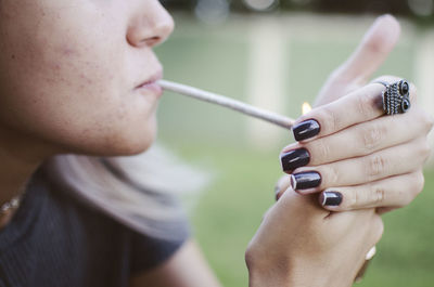 Close-up of woman igniting marijuana joint outdoors