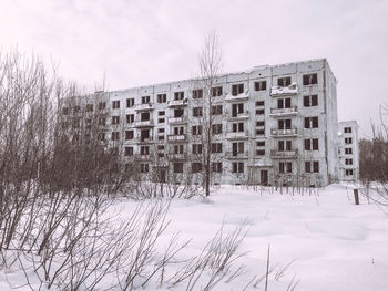 Buildings on snow covered field against sky