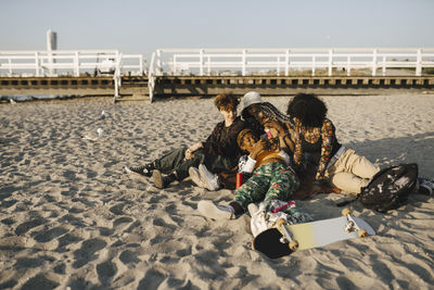 Lgbtqia friends sharing mobile phone at beach