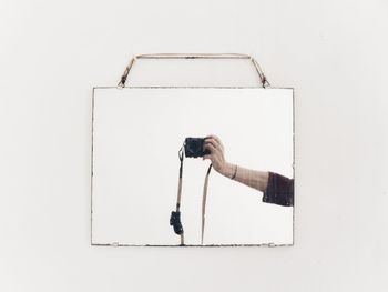 Man holding umbrella against white wall