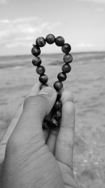 Close-up of human hand against sea