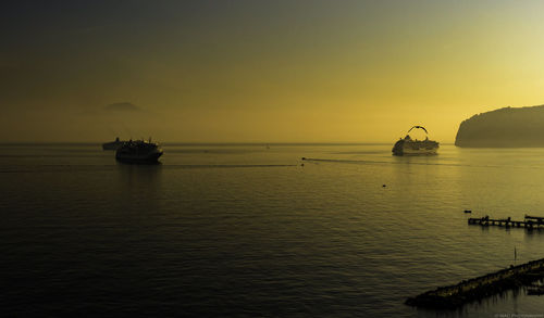 Cruise ships sailing in sea at sunset