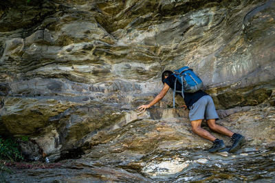 Young boy climbing the rocks wearing a backpack.