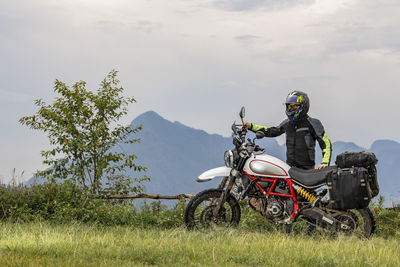 Man standing next to his scrambler type motorcycle