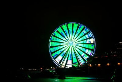Low angle view of illuminated ferris wheel against sky at night