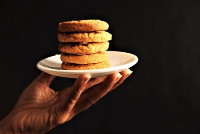 Close-up of hand holding stack against black background
