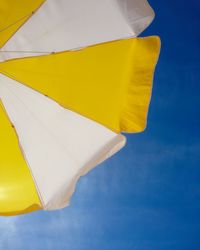 Low angle view of yellow flag against blue sky