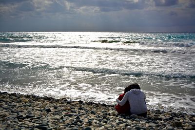 Rear view of woman standing on beach against sky
