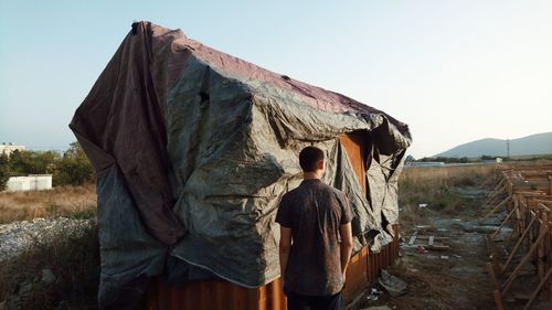 Rear view of man standing by cargo container on field