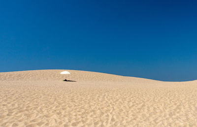 Sand dunes in desert against clear blue sky