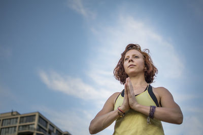 Woman exercising against sky