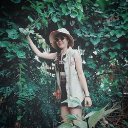 Young woman standing against plants