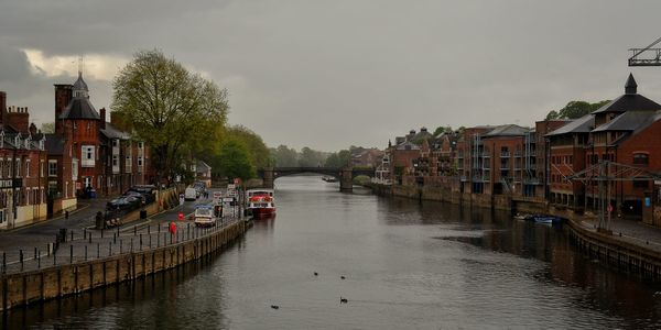 View of canal in city against sky