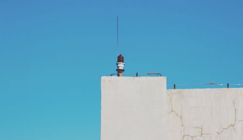 Low angle view of man working on building against blue sky