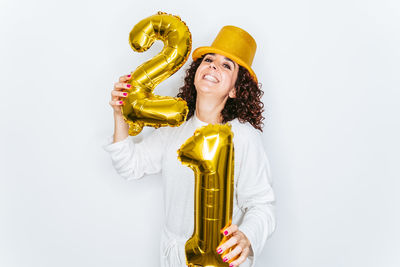 Portrait smiling woman wearing hat holding balloons against white backgrounds