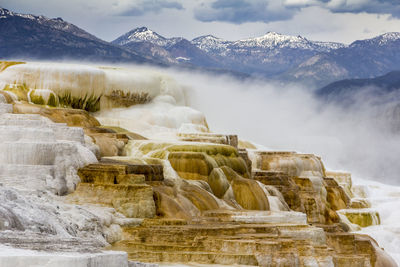 Scenic view of travertine pool against mountains at mammoth hot springs