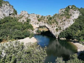 Scenic view of river by mountains against blue sky