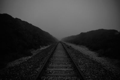 Railroad tracks against sky at night