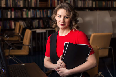 Professional woman educator or manager posing at public library of high school or college