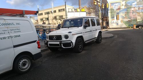 Car on city street by buildings against sky