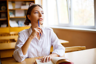 Focused millennial female student sits in classroom studying with writing