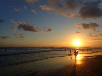 Silhouette person on beach against sky during sunset