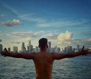 Rear view of shirtless man against buildings in city