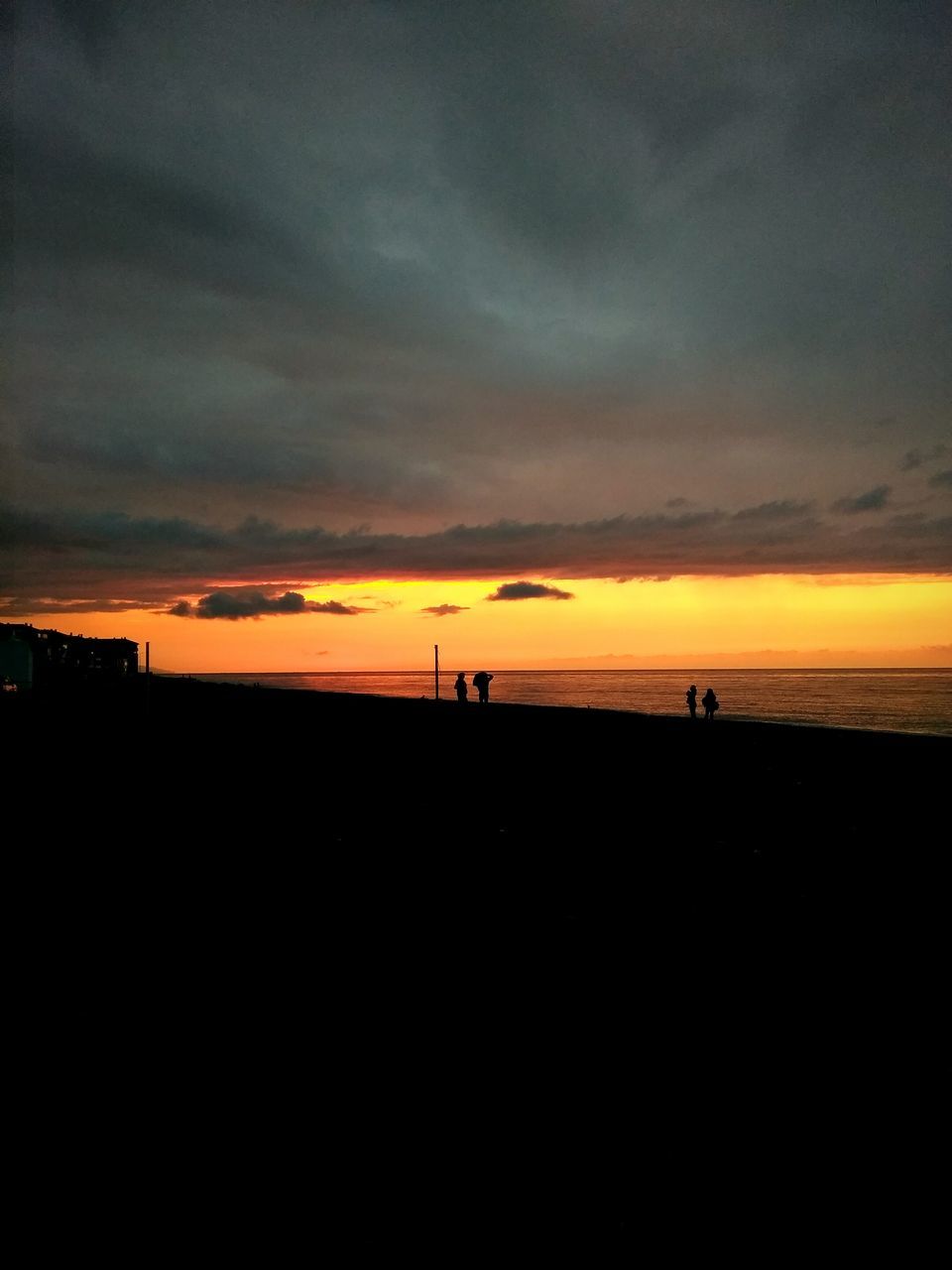 SILHOUETTE OF BEACH AGAINST DRAMATIC SKY