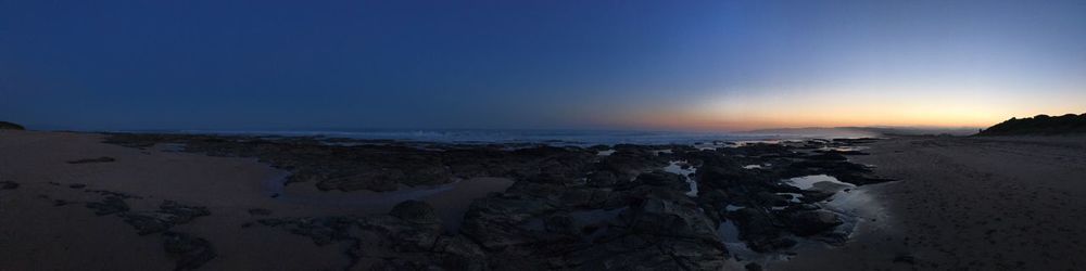 Scenic view of beach against sky at sunset