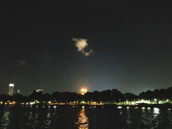 River by illuminated city against sky at night