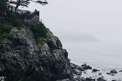 Rocky cliff by sea against sky