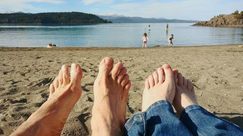 Low section of bare feet relaxing on shore