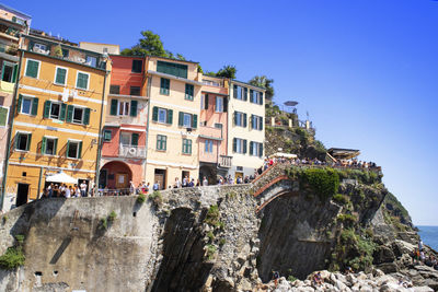 Buildings by sea against clear blue sky