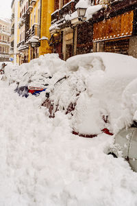 Snow covered street amidst buildings in city