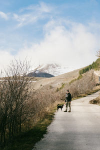 Rear view of man walking on snow covered landscape with dog