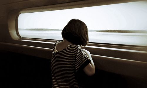 Rear view of woman looking through train window