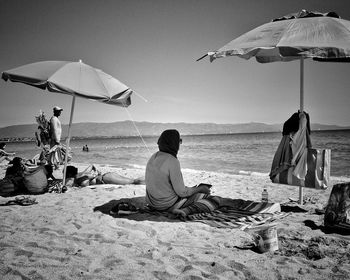 People sitting on beach by sea against sky