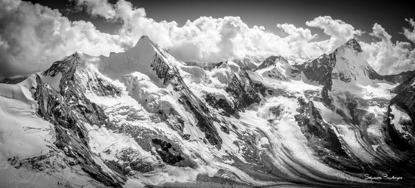 Scenic view of snowcapped mountains against cloudy sky