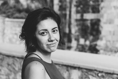 Portrait of smiling young woman against wall